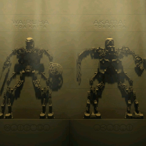 Image. Carvings of the two Toa Kaita, Akamai and Wairuha. They are tall and alien, with huge legs and tiny arms. Above them are inscribed their names in English. Below them, the names are written in the Bionicle language.